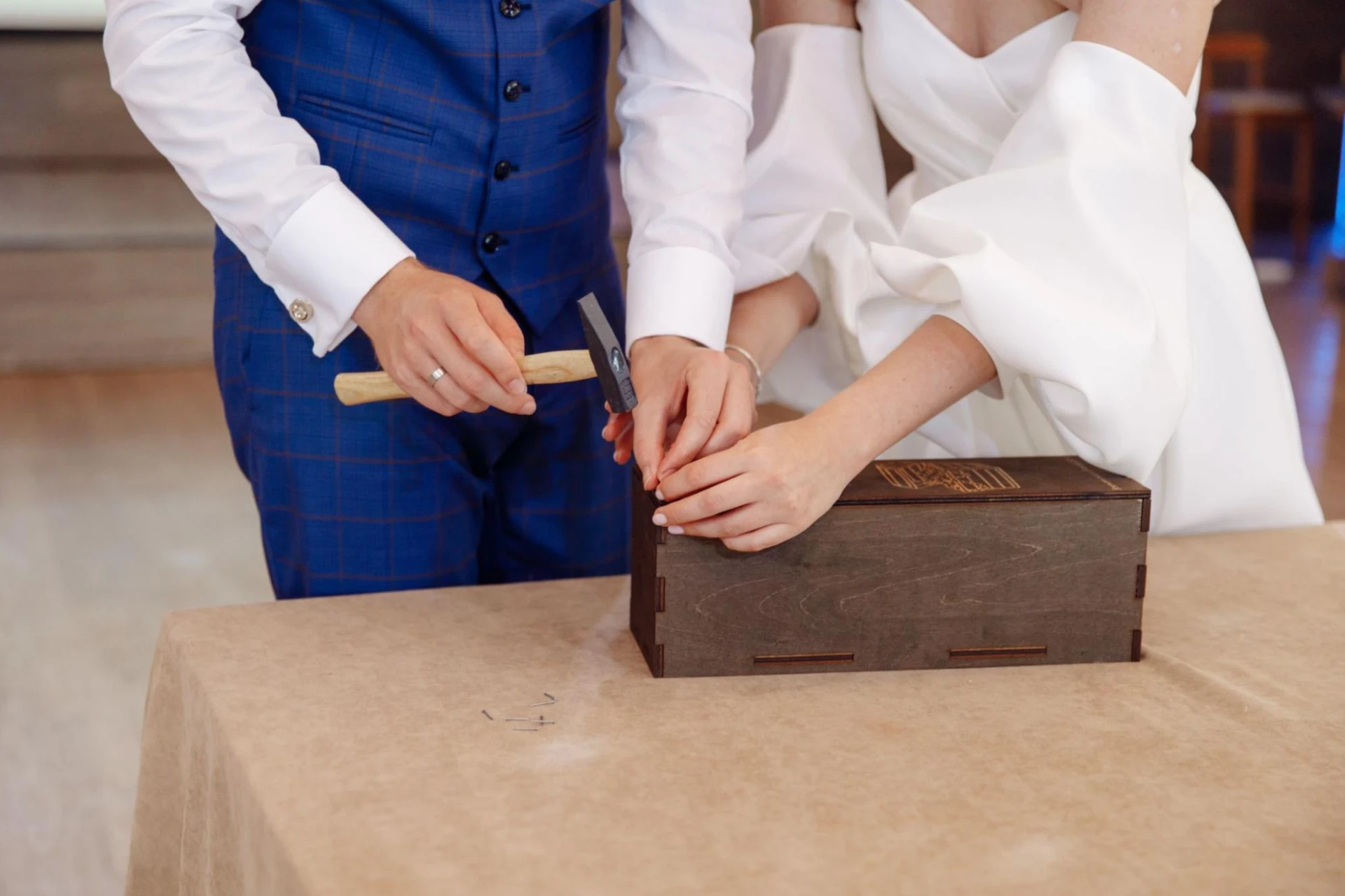 Bride and groom hammering nails into a traditional ceremony box