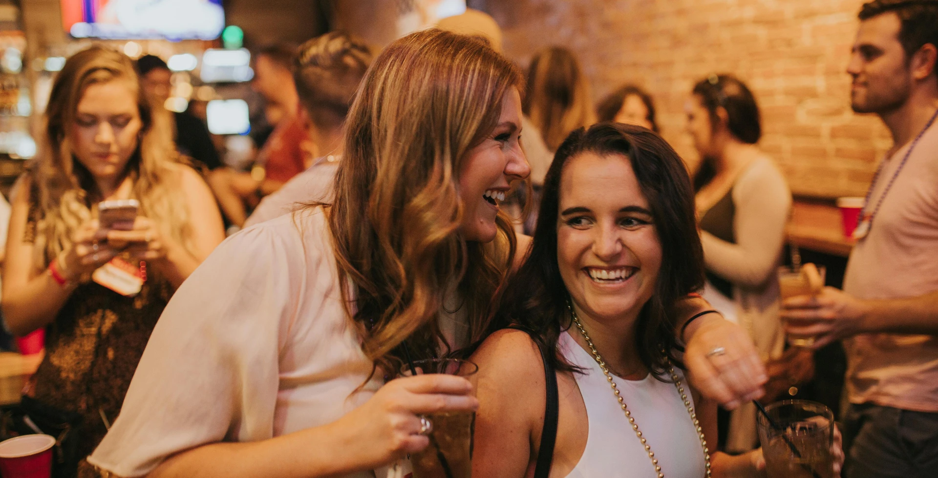 A group of friends holding red cups at a sports viewing part in a loft-style venue