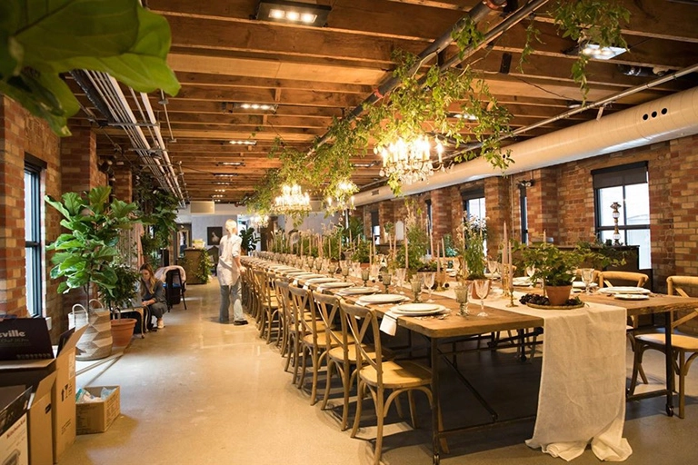 A decorated dinner table under chandeliers in a loft.