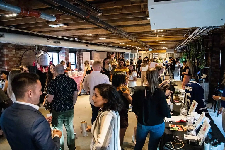 A brick and wooden loft space packed with guests socializing.