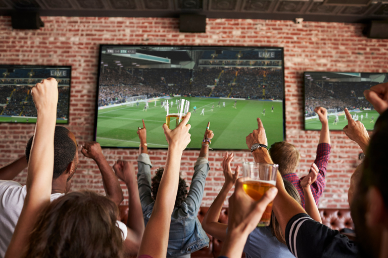 A group of people watching soccer on three big screens