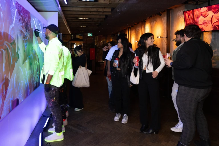 Guests drawing on a wall with LED projections for the Madri event at Baro Toronto