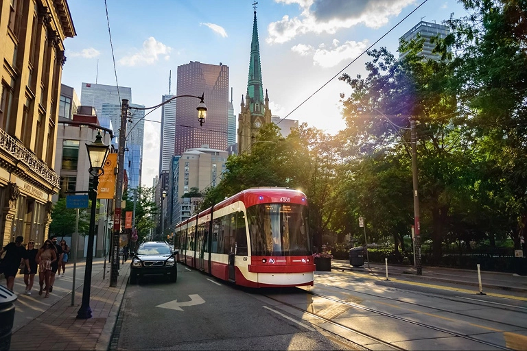 A streetcar drives by a park in Toronto in the summer