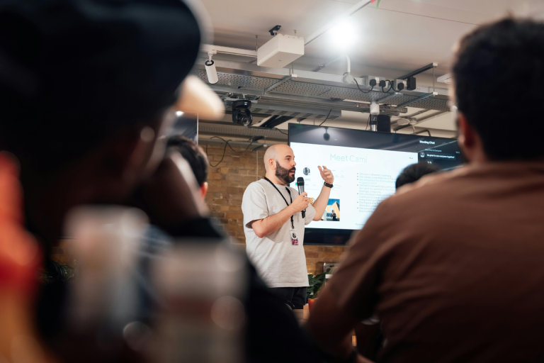 A speaker presenting at a conference in a loft-style venue