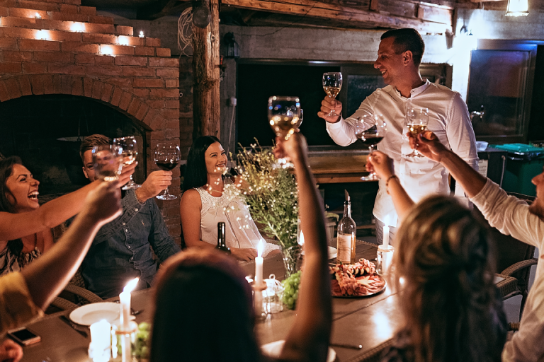 A group of friends having a romantic candlelit dinner in a loft venue with exposed brick and string lights 