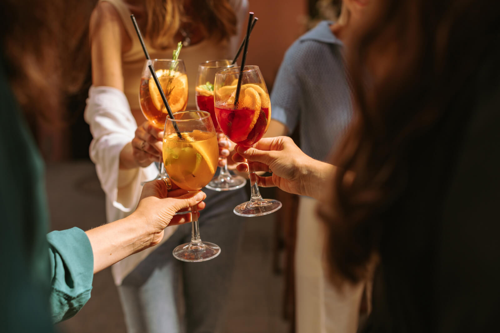 Four people toasting summer cocktails at a party