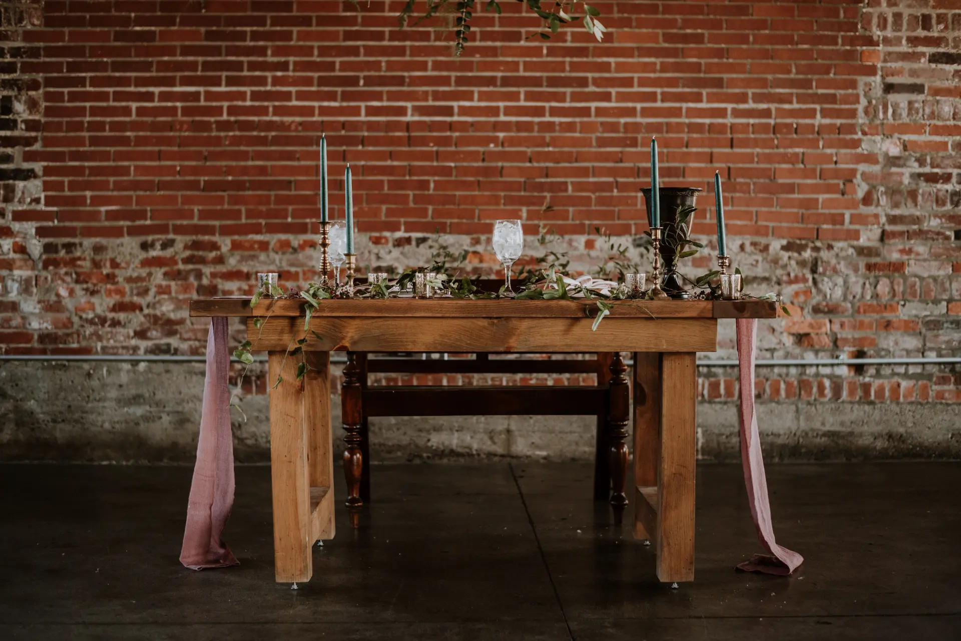  Sweetheart table set against an exposed brick wall in a rustic industrial-chic venue 